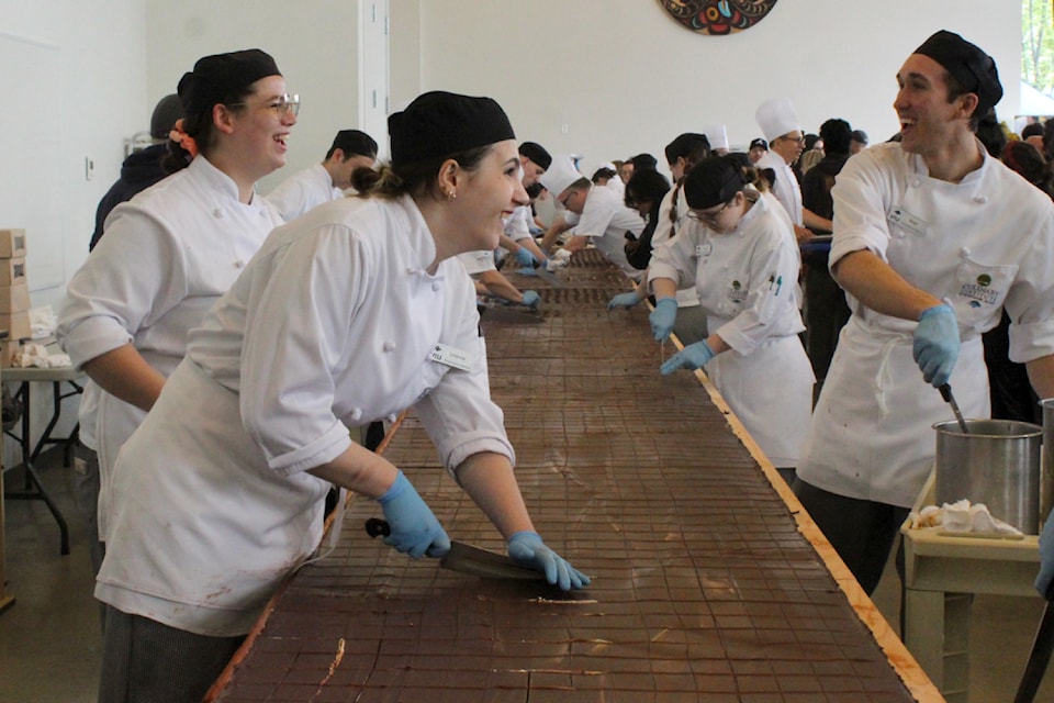 VIU professional baking students Aloura Brown-Collicott, left, Lilianna Dinunzio and Noah Rosnau cut up the world's largest Nanaimo bar on Saturday, May 17. (Greg Sakaki/News Bulletin)