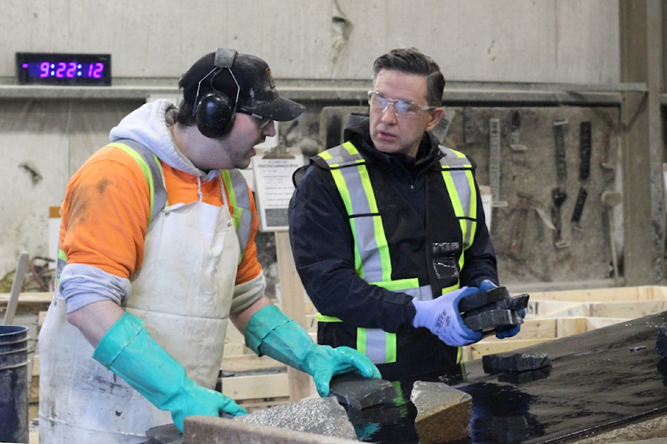 Murray Funk, a labourer at K2 Stone Manufacturing, left, gets some help on the job from Pierre Poilievre, leader of the Conservative Party of Canada, during a tour of the workplace Tuesday, Jan. 14. (Greg Sakaki/News Bulletin)