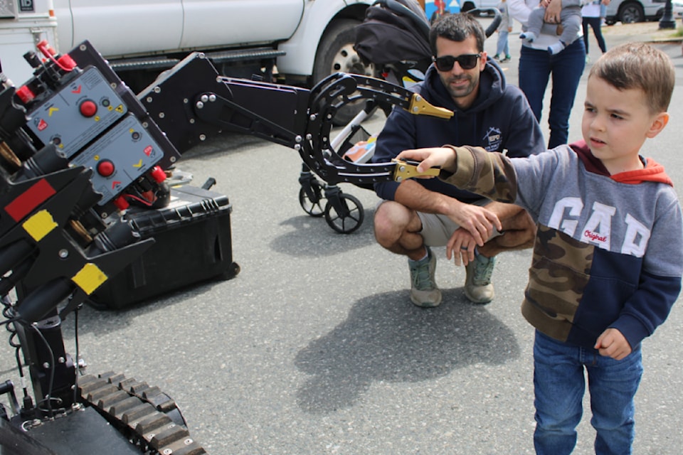 Kayce Rushton shakes hands with an ICOR Technology bomb disposal robot while father Adam looks on. (Karl Yu/News Bulletin)