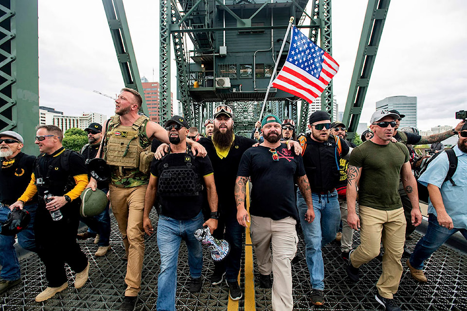 Members of the Proud Boys and other right-wing demonstrators march across the Hawthorne Bridge during an “End Domestic Terrorism” rally in Portland, Ore., on Saturday, Aug. 17, 2019. The group includes organizer Joe Biggs, in green hat, and Proud Boys Chairman Enrique Tarrio, holding megaphone. (AP Photo/Noah Berger)