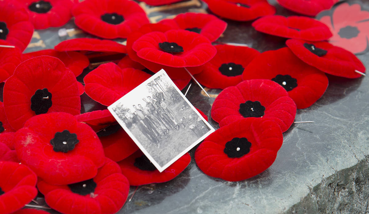 A old photograph is laid among a pile of poppies during a maritime Remembrance Day ceremony in Burrard Inlet in North Vancouver, B.C., Monday, November, 11, 2019. THE CANADIAN PRESS/Jonathan Hayward