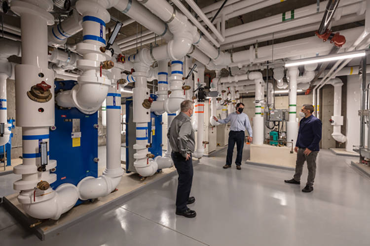 Colin Richardson, Energy Systems Manager, UBCO; Glen McIntyre, Thermal Energy Manager, UBCO; and Juan Rincon, Key Account Manager, FortisBC, tour the utilities area of the Commons building at the UBCO campus.