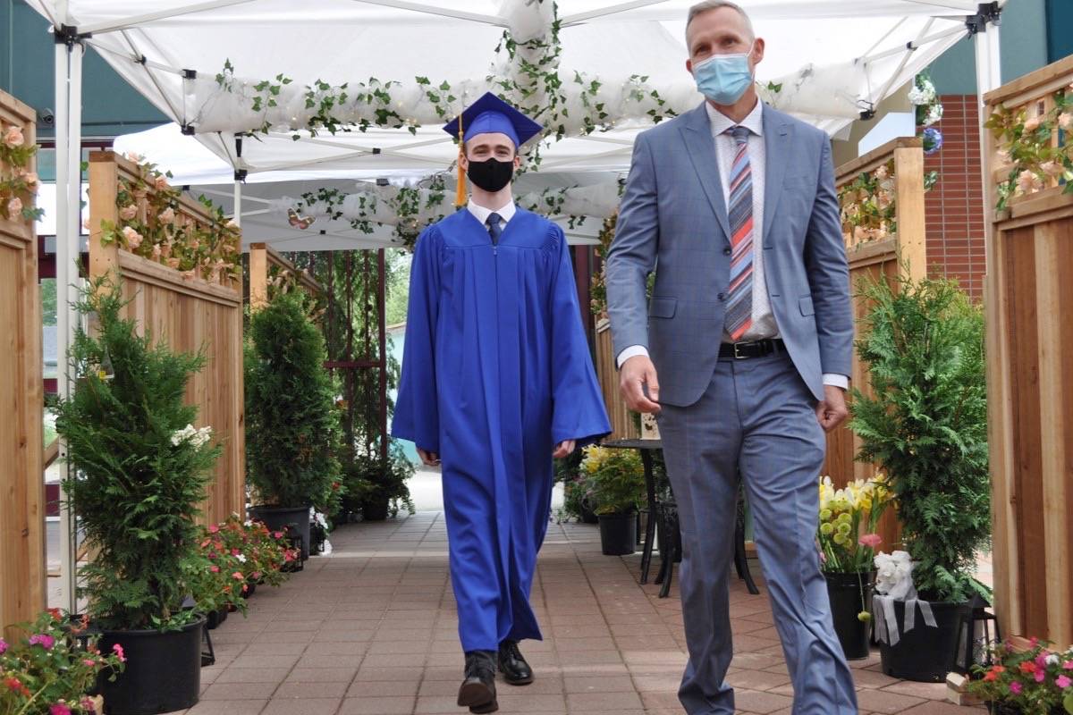 L.V. Rogers graduate Jack Ross and principal Ben Eaton walk down a special corridor set up for the individual cap and gown ceremony at Nelsons high school. Photo: Tyler Harper