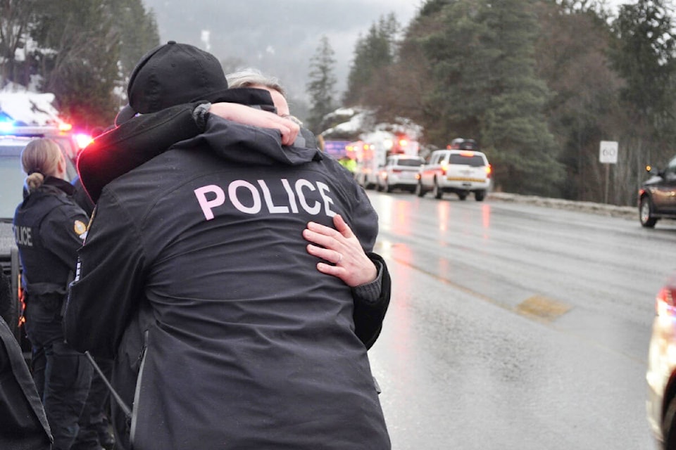Nelson Police Department Sgt. Corey Hoy and an onlooker embrace Thursday as a convoy carrying Const. Wade Tittemore’s body arrived in Nelson. Photo: Tyler Harper