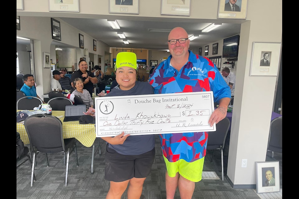 Linda Khounkhong, left, accepts the big cheque from Shaun Morris after her win in the Mediocre Golf Association's Yellowknife Douche Bag Invitational at the Yellowknife Golf Club on Sunday. Photo courtesy of Shaun Morris
