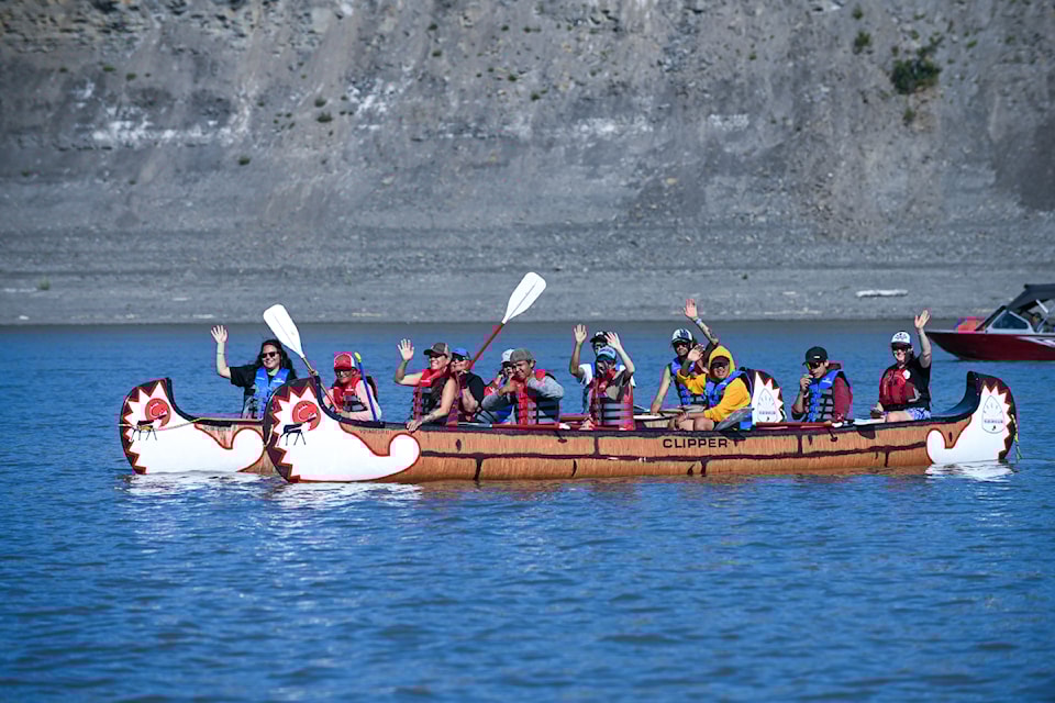 Two teams wave as they set out onto the Mackenzie River.