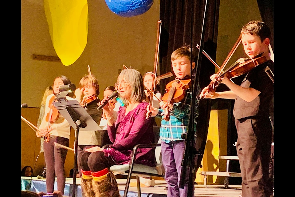 Tlicho Elder Rosa Wah-Shee is surrounded by fiddlers as they accompanying her while she reads her poem, SAӰӴýOde to the Northern LightsSAӰӴý, during the winter concert at N.J. Macpherson School. Photo courtesy of Sean Daly