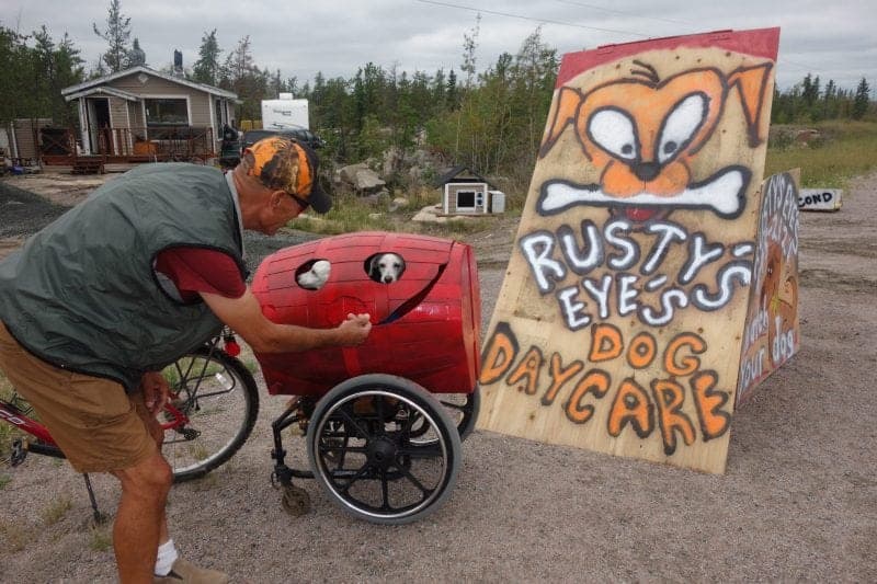 Aug 22/17 John McFadden/NNSL photo John Lemouel coaxes his two dogs Benjamin and Paiden to poke their heads out of his homemade dog trailer on Tuesday. Lemouel opened Rusty's Eye's Dog Daycare in his home on Hwy 3 outside of the city this summer. For a donation, he will take care of people's dogs, providing an option to boarding kennels or dog-sitters.