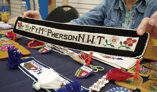 Emelie Peacock/NNSL photo Patsy June Krutko holds up a sash she beaded displaying the name of her hometown Fort McPherson. Krutko was camera shy, but not too shy to show her art at a gallery set up by the Department of Industry, Tourism and Investment in Yellowknife.