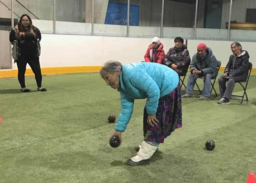 Lydia Palluannuk tries her hand at bocce on the turf at the Iglulik arena. In the background, from left, are community health representative Lucy Sarpinak, standing, and Sirpaapik Ammaklak, Martha Qattalik, Theo Ikkumaq and Leonie Qrunnut.  Jose Quezada photo 