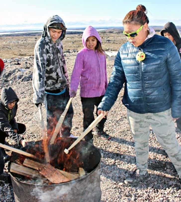 Grade 8 student Roger Ammaroalik, from left, Grade 7 student Andrea Uttak and Grade 9 student Heather Putulik enjoy the bonfire during Embrace Life activities at Tuugaalik High School in Naujaat on Sept. 28, 2018. Photo courtesy Julia MacPherson