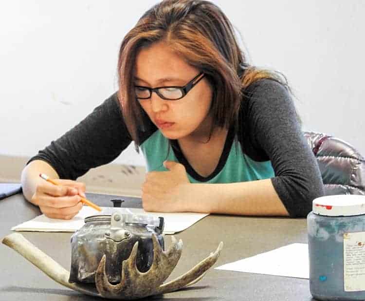 Falisha Niakrok works carefully on a pencil sketch during a Kivalliq Inuit Art Camp held in Naujaat on June 29, 2017. NNSL file photo