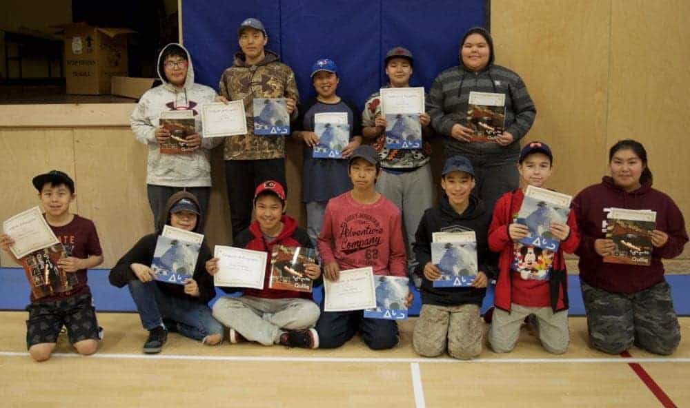 Proudly displaying their certificates of recognition and their Inuktitut books for their Literacy Week assignments are, front row, from left, Andrew Palongayak, John Qirqqut, Gabriel Nimiqtaqtuq, Pauloo Pauloosie, Justin Tootalik, Bailey Rudolph and Sheridan Kamookak. Back row, from left, Paul Iquallaq, Michael Mariq, Alex Nimiqtaqtuq, Mark Kununak, Jade Kamookak. Others earning a certificate were Carissa Putuguq, Karen Aaluk and Jordan Takkiruq.