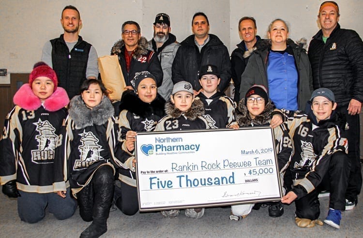 Rankin Rock peewee players, front row from left, Erin Kubluitok, Kaylen-Janne Nakoolak, Sophia Kaludjak, Kylan Saviakjuk, Jaidyn Verbeek, Kadin Eetuk and Simon Wiseman proudly display the $5,000 donation the team received from the Northern Pharmacy. Also taking part in the presentation are, back from left, Tim Smith (Northern Pharmacy), Hunter Totoo (donated 2,000 GN pins to the team), Joe Verbeek (Rankin Rock coach), Larry Fortes (Northern store), Dave Chatyrbok (Northern store), Rae-Lynn Steadwell (Northern store) and Dave Wiseman (Rankin Rock coach) in Rankin Inlet on March 7, 2019. Darrell Greer/NNSL photo