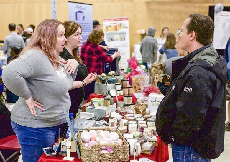 Tiffany Thiem-Pennell, left, chats with Al Matesic at the Good Times Soap Company booth at the trade show in 2017. Business owner Karen Wood can be seen chatting with a visitor in the background. The 2019 trade show begins tomorrow at the Multiplex, starting at 10 a.m.  NNSL file photo