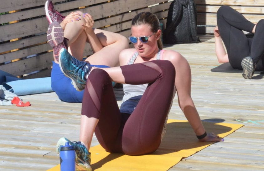 Madison Penney stretches out the legs during a cool-down following an outdoor workout on the patio at the Racquet Club on Saturday. The outdoor workouts at the club resumed on May 23. James McCarthy/NNSL photo 
