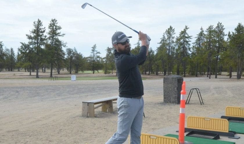 Cole Marshall, general manager and head pro at the Yellowknife Golf Club, admires a practice shot on the driving range on Sunday. Note the orange pylon to Marshall's left, indicating that every other tee box on the range is closed off due to distancing procedures instituted at the club this season. James McCarthy/NNSL photo
