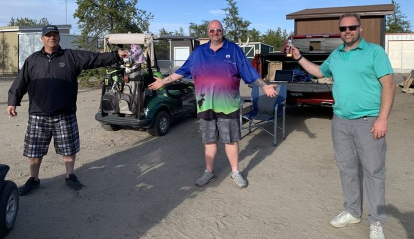 Daryl Snow, left, and Chris Hewitt, right, accept their physically-distanced trophies from Shaun Morris, president of the Mediocre Golf Association's Yellowknife chapter, after winning the team portion of the Rebel Beach Am-Am at the Yellowknife Golf Club on Saturday. photo courtesy of Shaun Morris