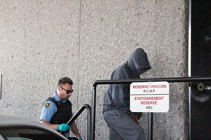 Brendan Burke/NNSL photo Wilfred Abraham, 54, covers his face as he enters a Yellowknife courthouse in handcuffs Thursday. Abraham has been charged with second-degree murder for the death of 48-year-old Ralph Sifton. 