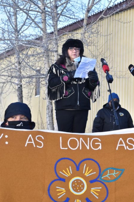 Nora Taylor, left, holds up a banner as Johanne Black, director of treaty, rights and governance with the Yellowknives Dene First Nation (YKDFN) speaks at the demonstration. Jason Snaggs, CEO of YKDFN stands behind Black. Blair McBride/NNSL photo