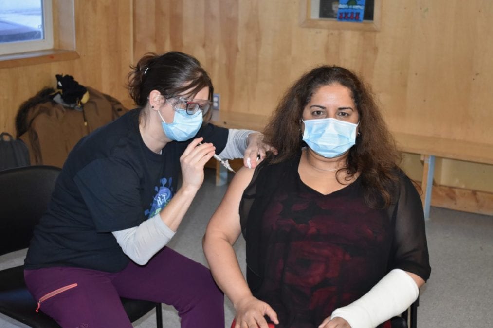 Teresa Patzer, left, gives chief public health officer Dr. Kami Kandola a shot of the Moderna vaccine in the Youth Centre in Wekweeti, on Wednesday. Blair McBride/NNSL photo