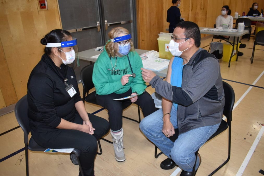 Student nurse Erica Abel, left, and Janie Neudorf, a nurse practitioner explain the vaccination procedure to Ernest Betsina, chief of the Ndilo Yellowknives Dene First Nation, on Saturday. Blair McBride/NNSL photo
