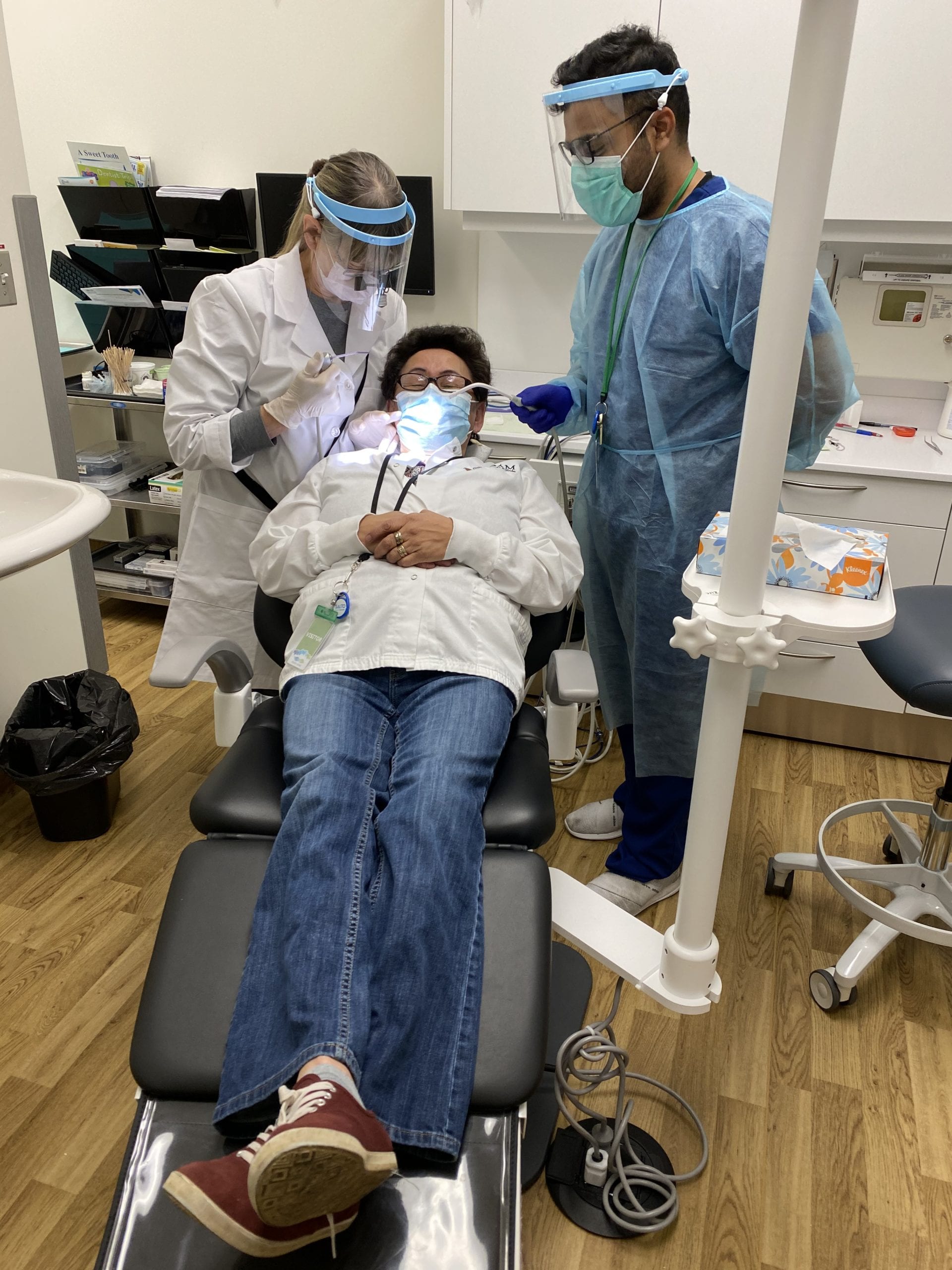 Dr. Pirjo Friedman, left, tests a dental light on receptionist Clara Kelly as assistant Kaushik Varadha holds a suction unit. photo courtesy of Pirjo Friedman