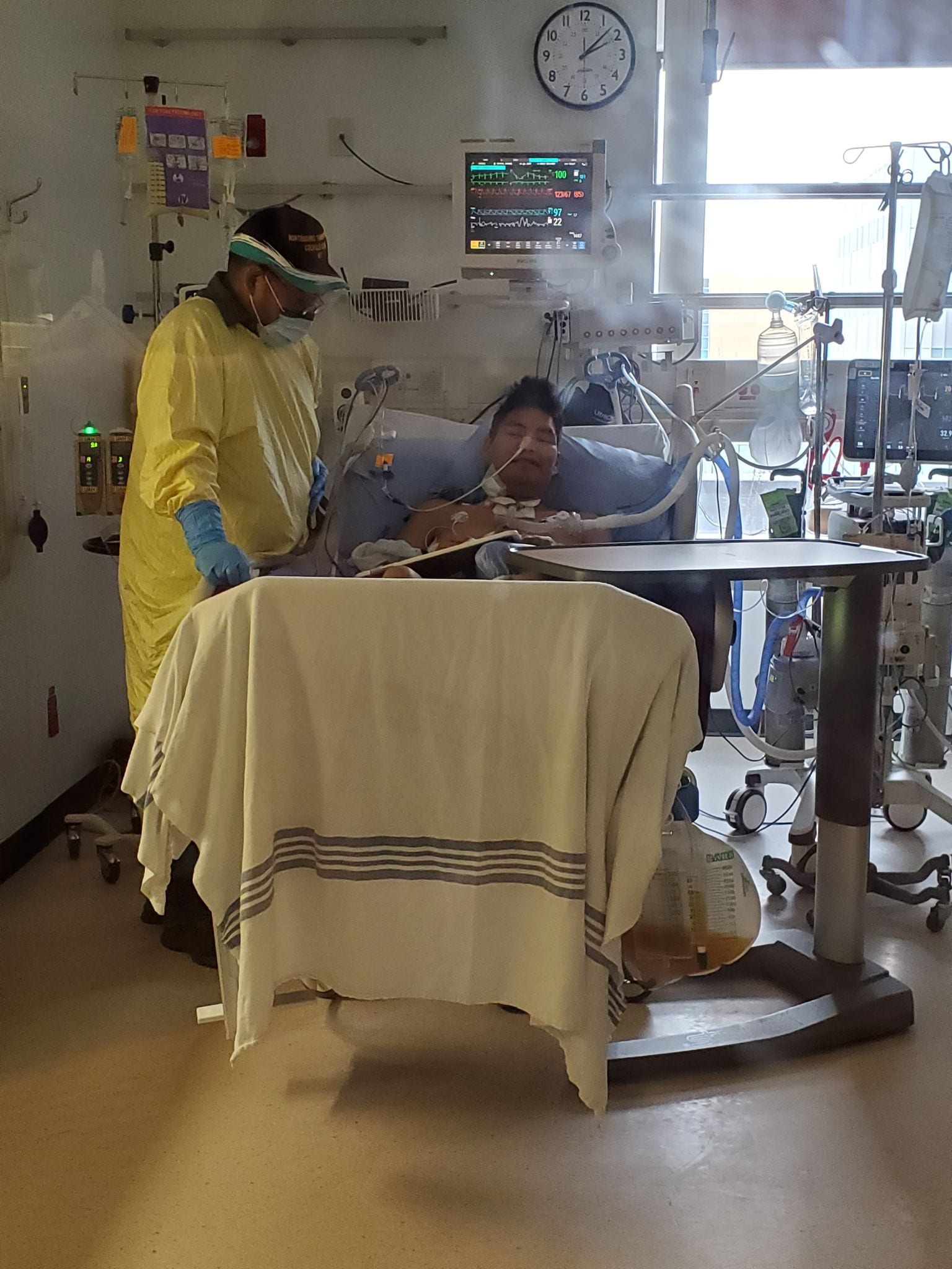 Wayne Kafkwi, left, stands by his son Myrine in the University of Alberta hospital in Edmonton, on Monday. Myrine's condition has improved his Saturday, after he came out of a coma and is able to breathe with less assistance from a ventilator, said his mother Dolly Pierrot. photo courtesy of Dolly Pierrot