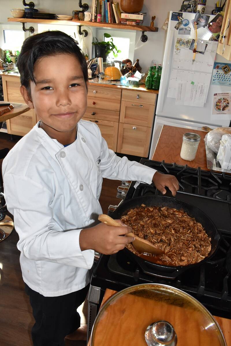 Drew Sinclair stirs up some pulled pork that he will add to his pulled pork poutine dish for his family on Sept. 6. Blair McBride/NNSL photo