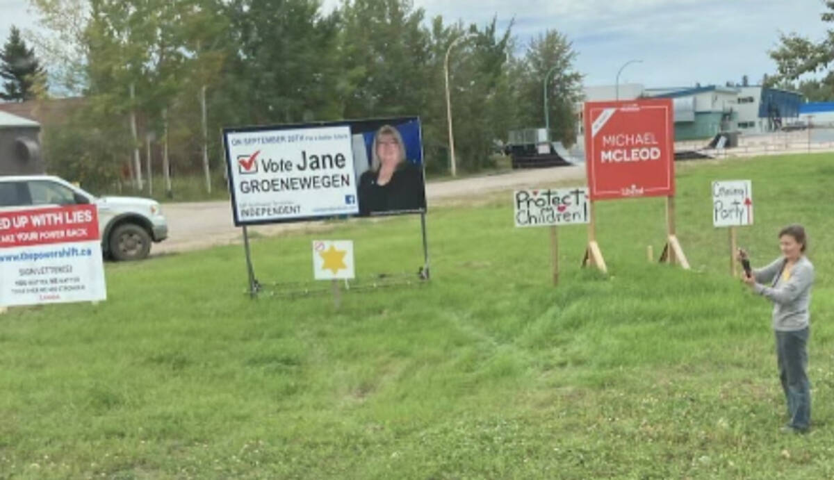                           Makeshift Stop the Mandates, in reference to required COVID-19 vaccines, were put up briefly beside Michael McLeod and Jane Groenewegen signs near Super A Foods. Jackie Milne, who helped put up some of the signs, is pictured at right. Simon Whitehouse/NNSL photo          