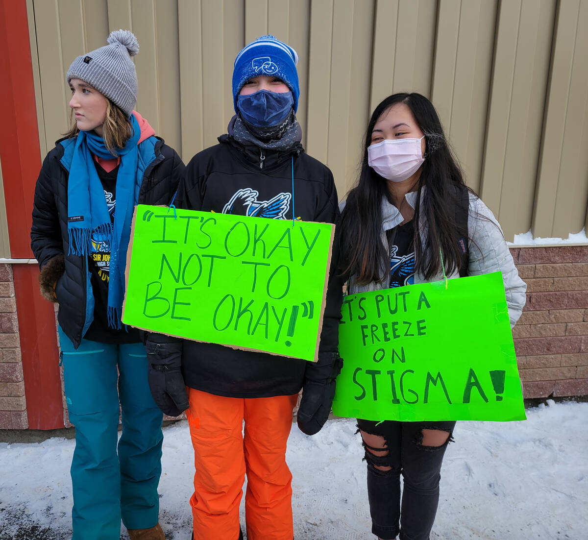 Ella Ireland, left, Jimena Maule, and Qui Giang with signs reading Its okay not to be okay and Lets put a freeze on stigma. Ethan Butterfield/NNSL photo