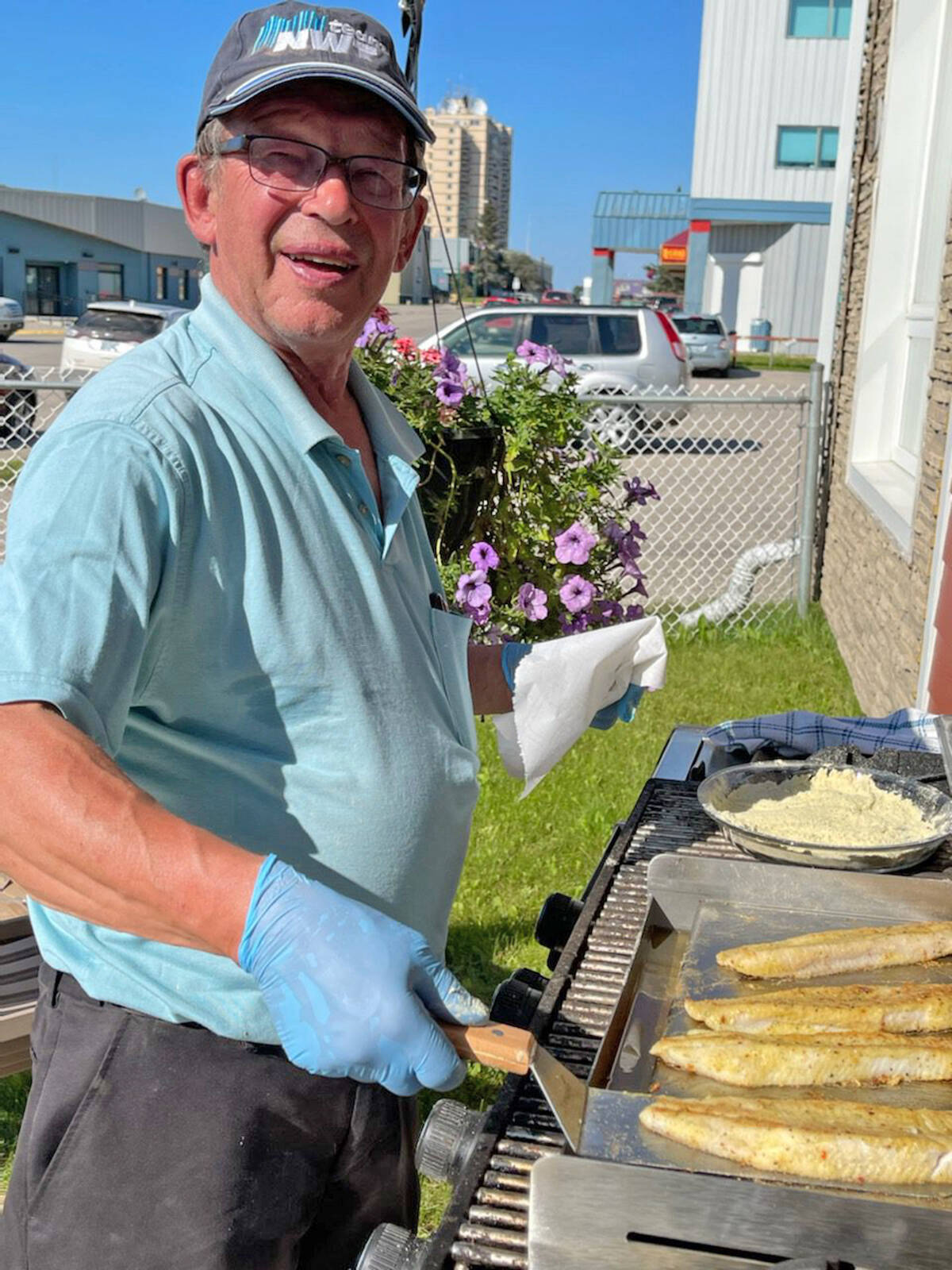 Tom Makepeace, chair of the Hay River Seniors Society grills fish under the sun July 31. The group was celebrating the completion of upgrades to the Alice Cambridge Room at the Whispering Willows seniors complex. The upgrades included a handwashing station, which was the only critical deficiency identified in an inspection for a food preparation permit Feb 14, 2020. Photo courtesy of Sandra Lester