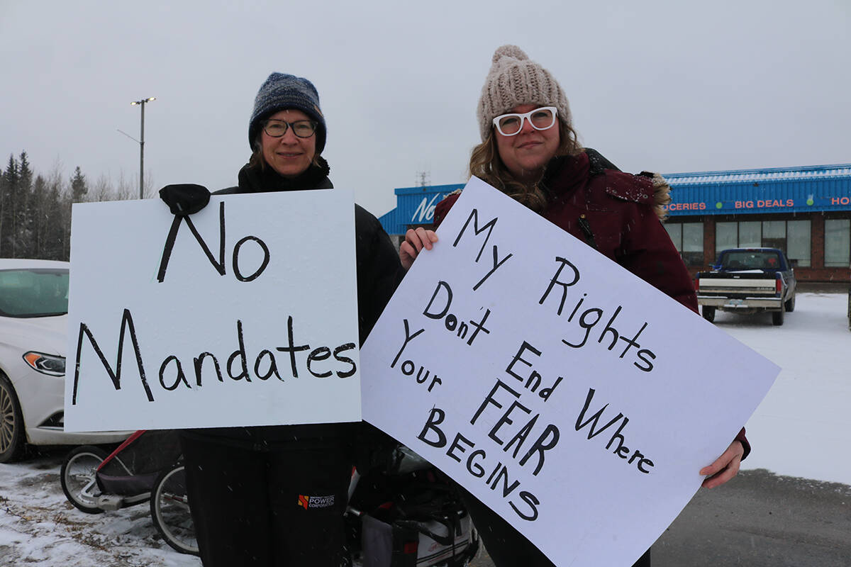 Donna Munro, left, and Amanda Campbell hold up their makeshift signs opposing mandatory vaccinations for Hay River traffic. About a dozen people demonstrated in front of the entrance to a grocery store Nov. 6. NNSL file photo
