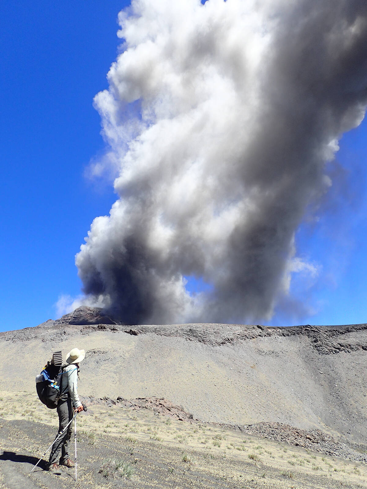 Lauren Reed looks up as a volcano erupts nearby while crossing the Andres mountains. Photo courtesy of Bethany Hughes and Lauren Reed