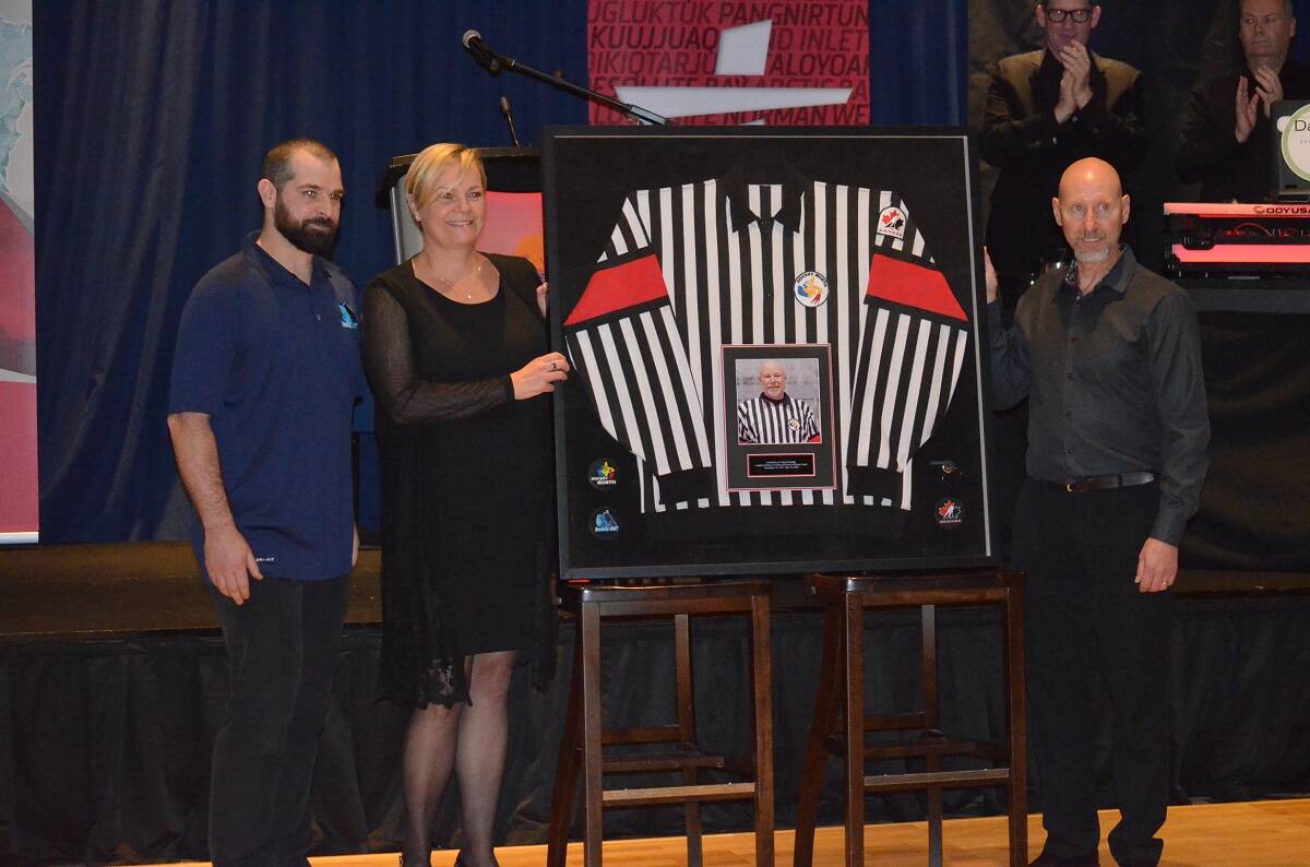 Kyle Kugler, left, Hockey NWTs executive director, and Darcy Milkowski, right, present Kim Knutson, wife of the late Craig Hockridge, with one of his jerseys during Hockey NWTs fundraising gala at the Explorer Hotel on Saturday, Oct. 15. James McCarthy/窪蹋勛圖厙 photo