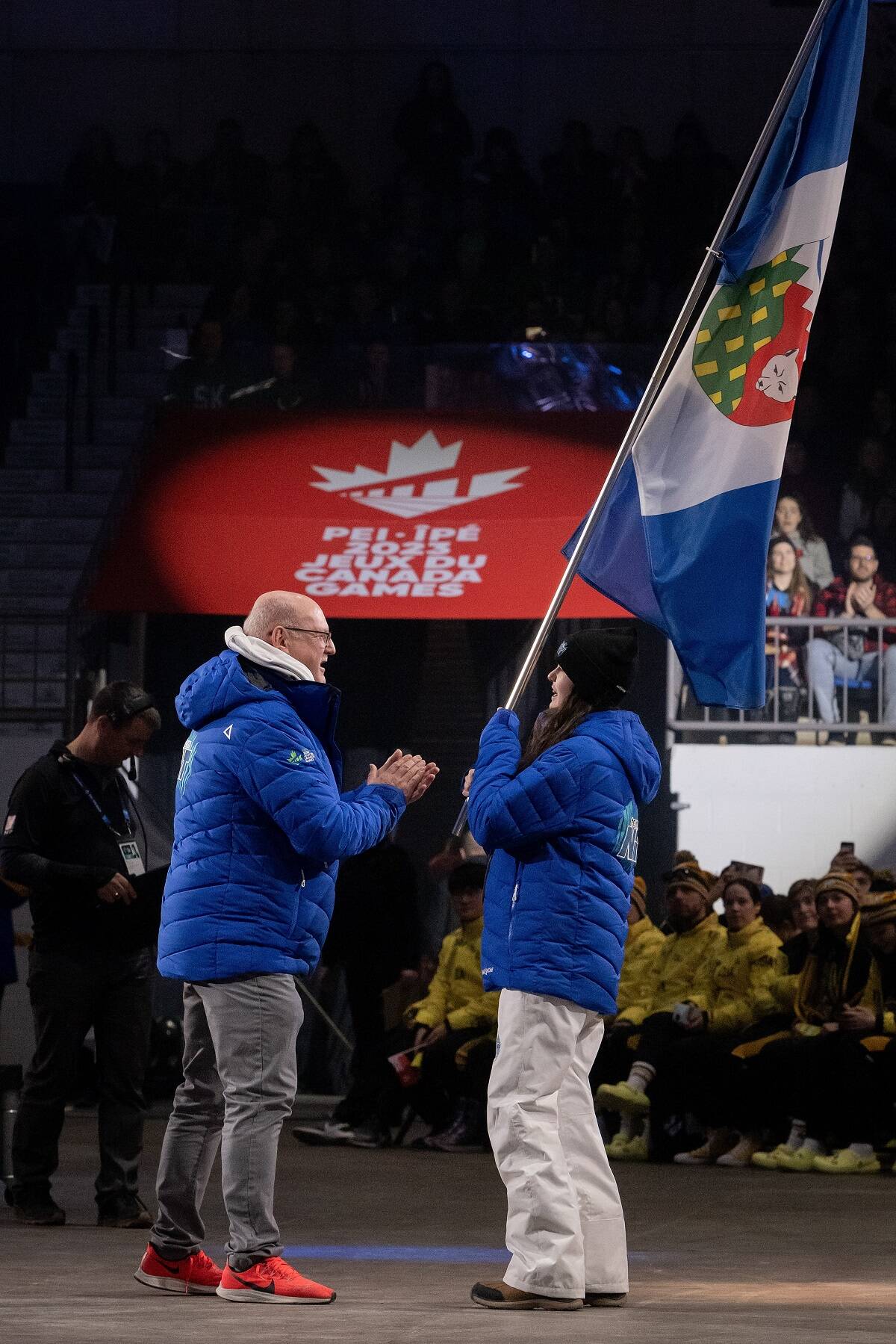 Sofia Ardiles, right, prepares to hand off the NWT flag to Shane Thompson, minister of Municipal and Community Affairs, during the opening ceremony of the 2023 Canada Winter Games in Charlottetown on Saturday. Matthew Murnaghan/Canada Games photo