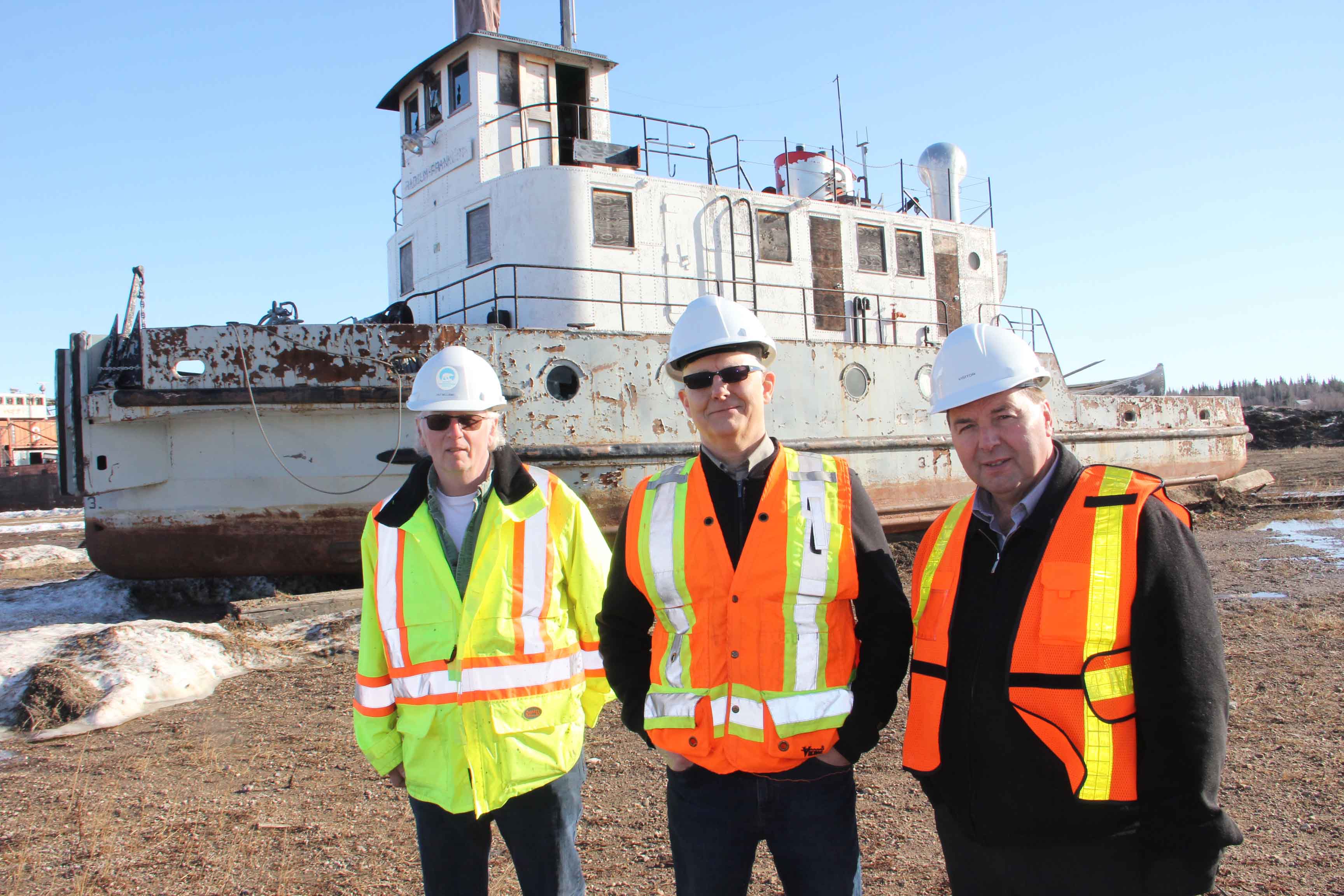 The Radium Franklin is being donated to the Hay River Museum Society by the GNWT's Department of Infrastructure. Standing in front of the vessel at the Marine Transportation Services Shipyard in Hay River on March 22 are, left to right, John Vandenberg, the assistant deputy minister of Infrastructure; Pat Williams, the assistant director of Marine Transportation Services; and Infrastructure Minister Wally Schumann. Paul Bickford/NNSL photo