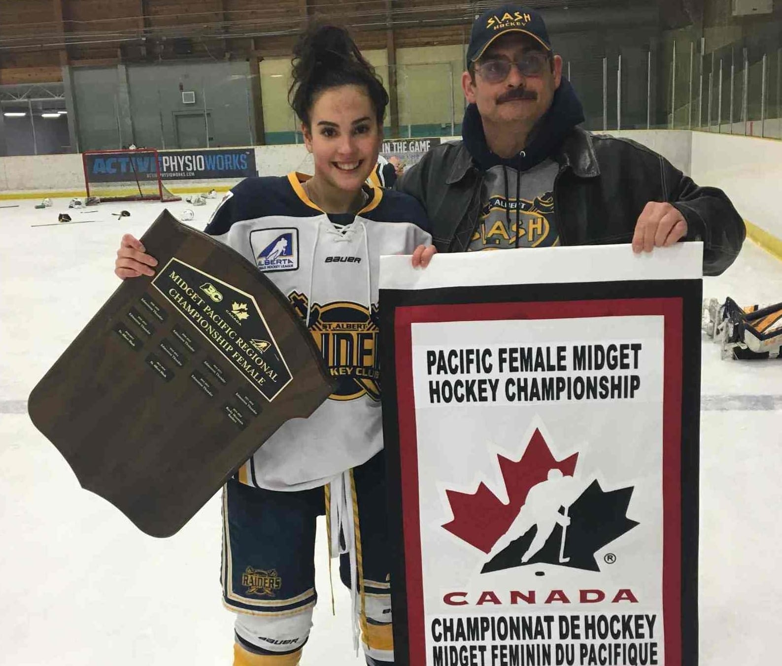Kiah Vail, left, shows off the championship banner her St. Albert Slash won on home ice on April 7 with her father, Roger Vail. She can now add the title of national champion as the Slash knocked off the Sudbury Lady Wolves of Ontario to win the Esso Cup on April 27, the third consecutive year the Slash have won the Canadian midget girls hockey championship. photo courtesy of Roger Vail