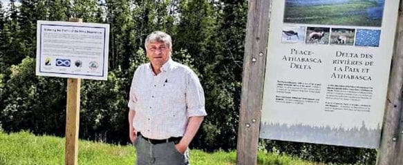 Ken Hudson, president of Fort Smith Metis Council, stands by signs Metis leaders posted in Wood Buffalo National Park in 2017 that illustrate the history of the Metis experience since the park was formed in 1921. Photo courtesy of Northwest Territory Metis Nation.
