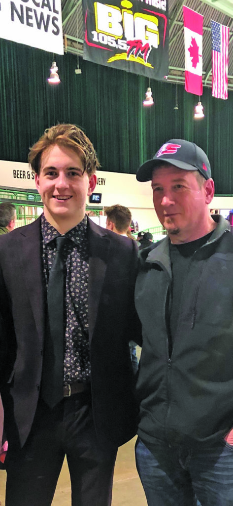 Logan Cunningham, left, is all smiles with his dad, Al Cunningham, after the junior Cunningham's first Western Hockey League game in Red Deer, Alta., in March 2020 with the Spokane Chiefs. photo courtesy of Shelley Cunningham