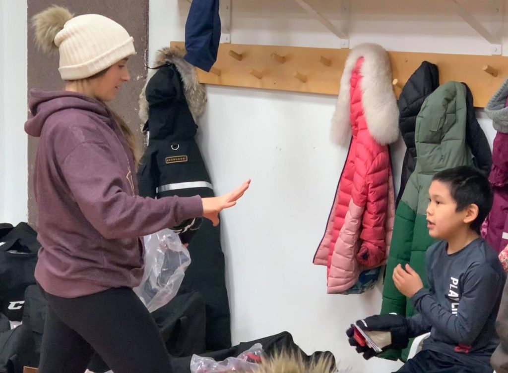 Katlyn Chalofer, left, checks with Kendrick Anavilok on his glove size during an equipment fitting at the community arena on Feb. 14. Photo courtesy of Matt Gee