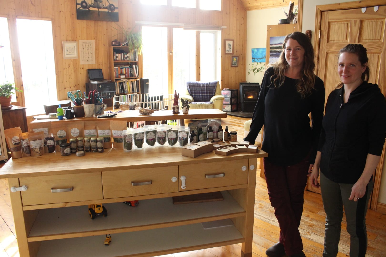 Amy Maund, right, founder of Laughing Lichen and Courtney Davison, operations supervisor, next to a sample of the wide range of wildcraft products made in Maund's off-grid home outside of Yellowknife. Maund has been using her lifetime or foraging skills and knowledge to build her company from once being at a farmers market to selling products across Canada. Brett McGarry NNSL/Photo