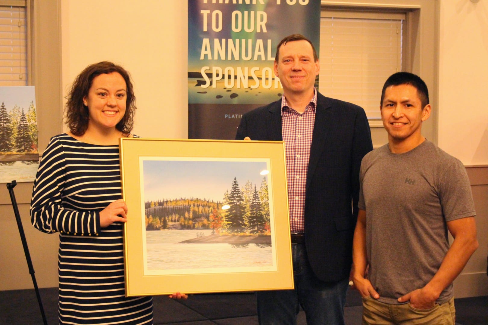 Brett McGarry/ NNSL Photo NorthwesTel's Paul Gillard and Darrell Chocolate, right, give a print of Chocolate's 'Serene Fall Season' to Mayor Rebecca Alty, to be hung in city hall. A print was also given to John MacDonald, Assistant Deputy Minister of Education, Culture and Employment.