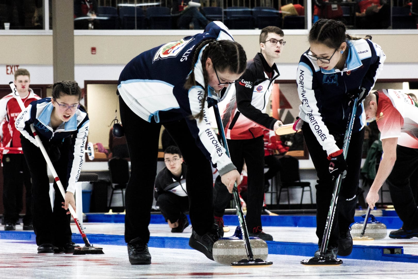 Pearl Gillis, left, shouts out the line as Mataya Gillis, centre, and Adrianna Hendrick put the brushes to the rock during girls curling action at the Canada Winter Game in Red Deer, Alta., on Monday. Mel Bolin/Canada Winter Games photo