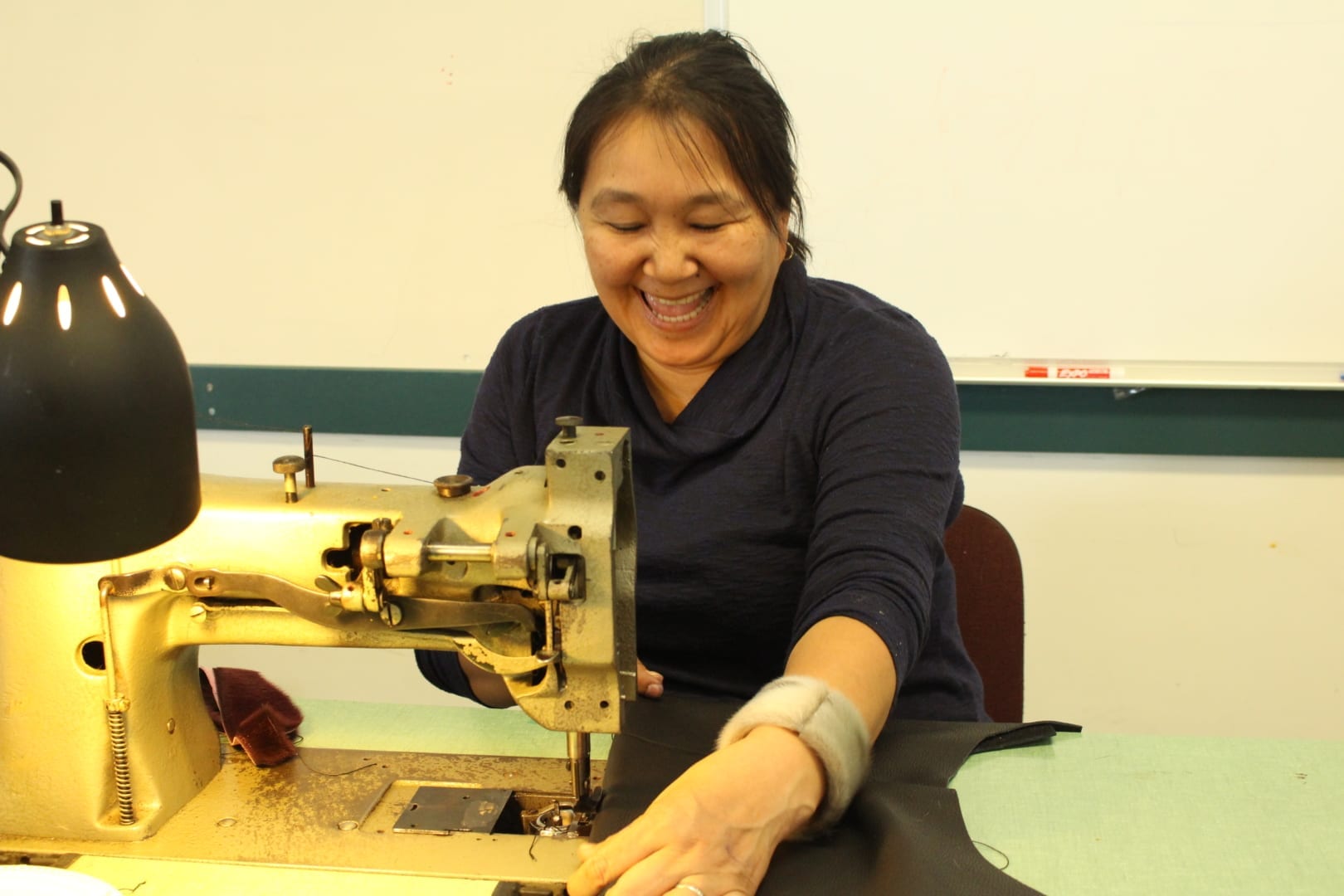 Susie Nakashuk-Zettler "showing off her good side" while sewing a piece of seal skin. She said being involved in the workshop and being surrounded by wonderful Indigenous artisans brought tears to her eyes. Brett McGarry