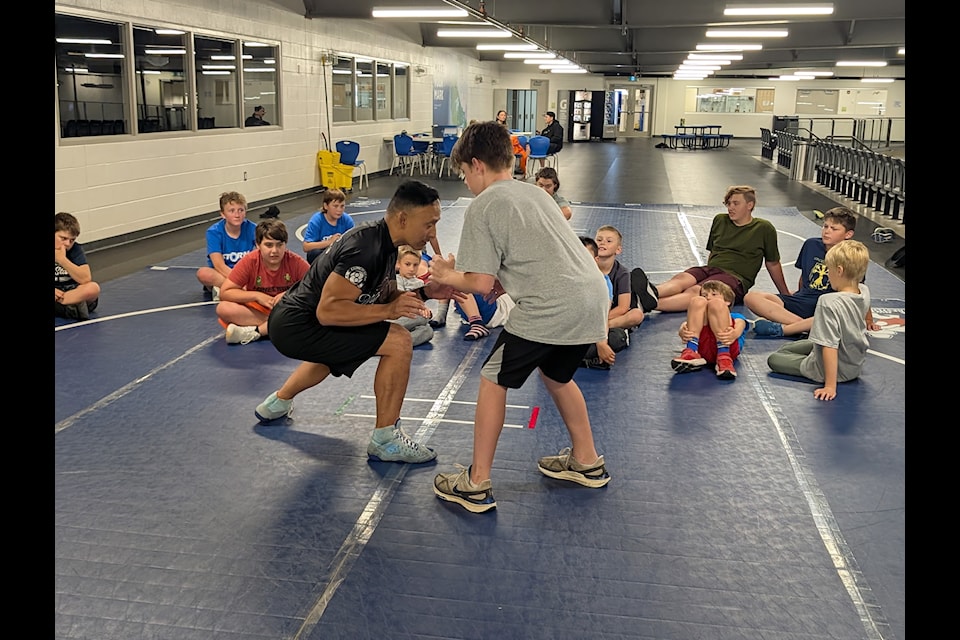 Ron Gonzalez, left, demonstrates how to get in low during a wrestling camp at the Aurora Ford Arena on Sunday. Photo courtesy of Heather Coakwell
