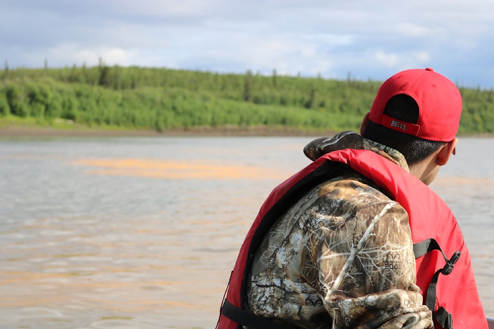 A boater looks out at a stretch of orange slime, which has been popping up in Northern waterways over the past decade. This shot was taken at Eight Mile near Fort McPherson in 2020.