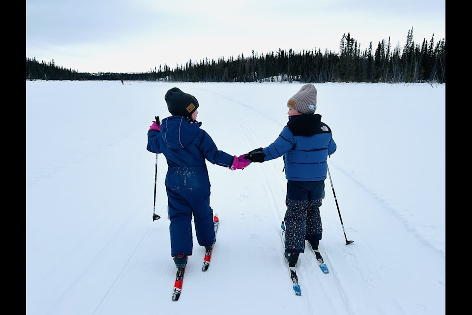 Two young skiers hold hands as they ski the course during the Yellowknife Gold Loppet. Photo courtesy of Alyssa Titus