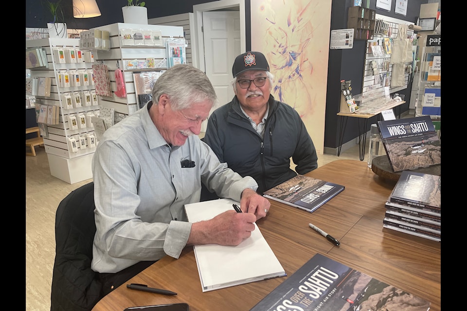 Warren Wright signs a copy of a new book, 'Wings Over the Sahtu,' for Paul Andrew. 
