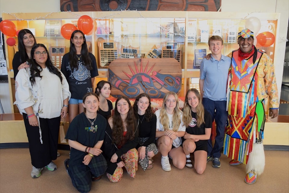 (From left) Burnsview Secondary students Sumeet Singh, Inayah Ismail, Meeka Khaira, Janne Hockley, Richie Jacobsen, Sofia Macgregor, Maisha Lindahl, Georgia Sheridan, Catalina Magnusson and Lucas Bircher unveil an Indigenous-inspired carving they made under the guidance of local artist and Delta School District child and youth care worker Curtis Miller Joe (right) that depicts a sea otter floating with an urchin  during a small ceremony at the school on Thursday, June 6, 2024.